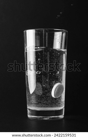 Tablet dissolving in a glass of water on black background