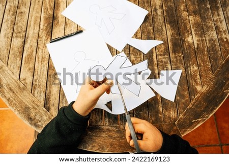 April Fool's Day concept. Child cutting papers with April Fool's Day dolls.