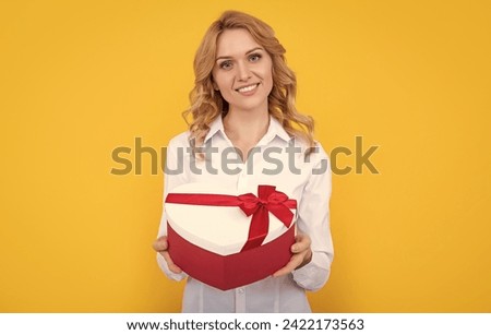 happy woman hold present heart box on yellow background