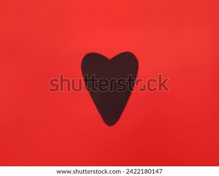 Black cardboard heart on a red background. Valentine's Day