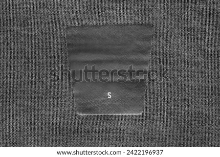 Size S clothes label on black fabric background closeup