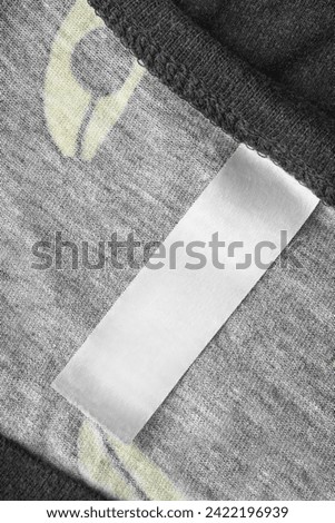 Blank clothes label on black knit fabric background closeup