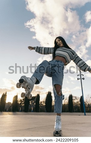 Girl in Roller Skates Playfully Lifting Leg Towards Camera. Playful smiling caucasian woman on roller skates, poised to step on the lens.