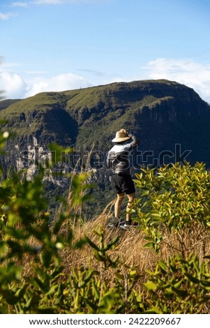man with hat with partial view of Kurun tepui from top of Kurawaina (Kuravaina) tepui mountain in sunny day. Canaima National Park, Venezuela