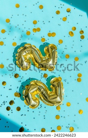 22 numbers from foil gold balloons on a blue background with confetti 