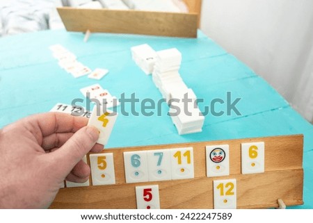 Plastic tiles from the game rummikub, rummicub or  okey in Turkey arranged on a wooden rack, on blue table background
