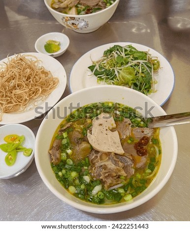 Bun bo Hue or Vietnamese Hue beef soup. Different from Pho, the meal is originated from Hue city. It is made of beef bone broth, fermented crab sauce, lemongrass, cinnamon. Eat with noodles, pork roll Royalty-Free Stock Photo #2422251443