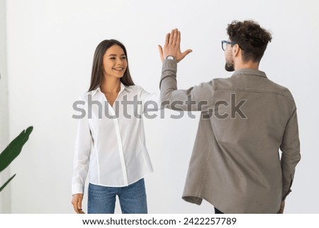 Picture of happy colleagues business team standing over white background isolated. Looking aside gives a high-five to each other.