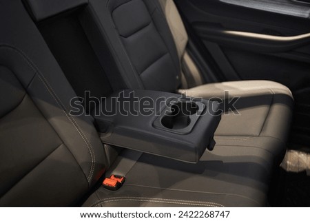 Armrest with cup holder inside. Leather comfortable white passenger seats and armrest. White leather interior of the luxury modern car. Modern car interior details. Rear passenger seats. Royalty-Free Stock Photo #2422268747