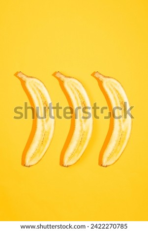 Top view on halfs of a bananas on yellow background. Delicious and healthy fruit Royalty-Free Stock Photo #2422270785