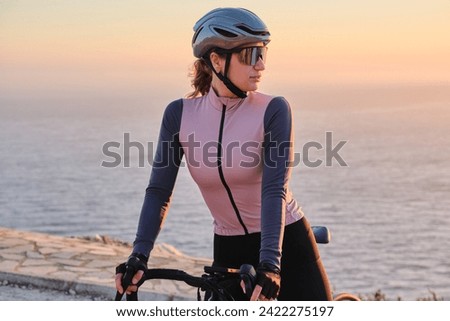Woman cyclist wearing cycling kit and helmet standing on sea background. Cycling motivation. Beautiful nature in background. Calp, Alicante, Spain