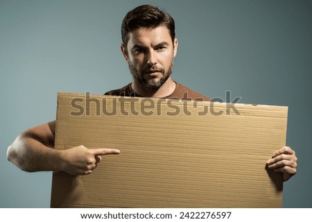 Handsome man holding empty board and pointing finger on board. Guy showing blank board with copyspace. Idea and offer. Your advertisement. Blank advertising board with empty space for text, mockup.