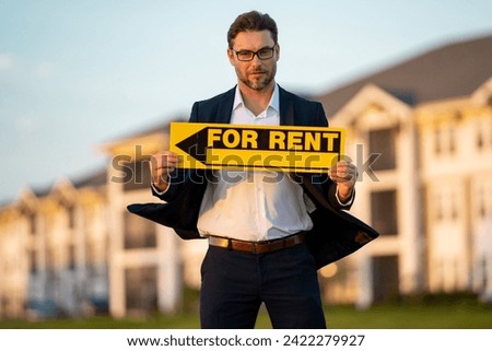 Real estate agent hold house rent sign. Real estate renting property. Rent new home. Handsome real estate agent in suit showing the house for rent. Rent home, rental concept. Renting an apartment.