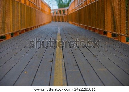 pedestrian wooden bridge, cyclist with orange metal structure, yellow signage