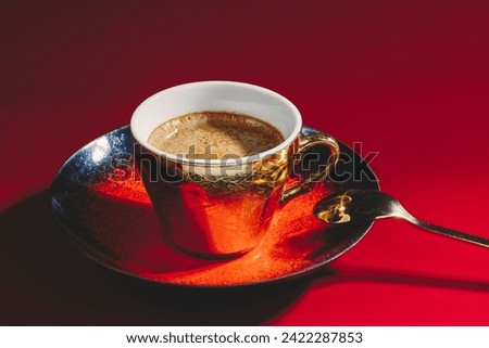 Coffee in a golden cup on a red background: A vibrant fusion, where the warm hues of the beverage harmonize with the bold red backdrop. Royalty-Free Stock Photo #2422287853