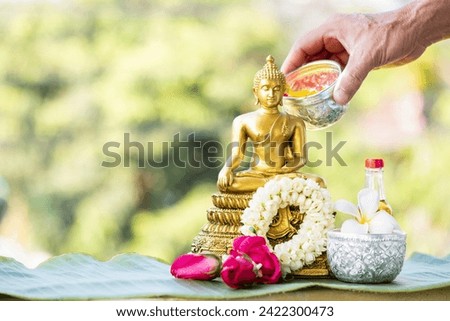 Sprinkle water onto buddha with water with flowers , thai traditional perfume and Jasmine garland to worship during the Thai Songkran festival. Royalty-Free Stock Photo #2422300473