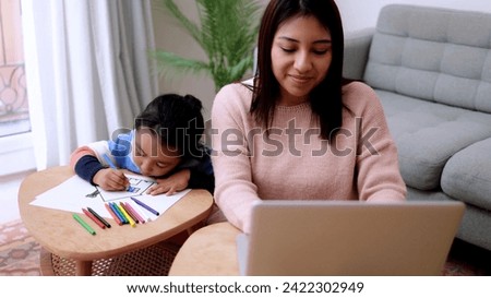 Asian mother taking care of her child painting while using computer laptop at home. Family lifes tyle Royalty-Free Stock Photo #2422302949