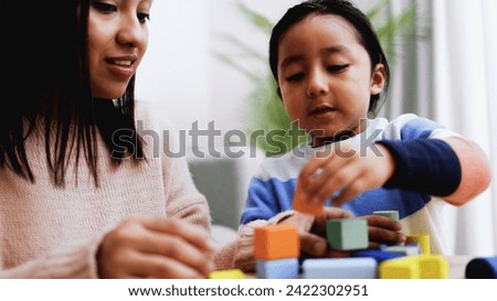 Latin American mother and son child having fun playing games with wood toy bricks at home. Education and family leisure time concept Royalty-Free Stock Photo #2422302951