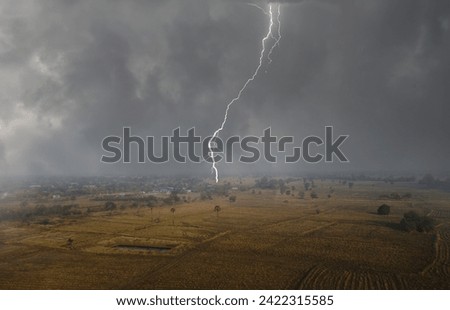 The first rain falls and scary lightning strikes over dry rice fields in Thailand Royalty-Free Stock Photo #2422315585
