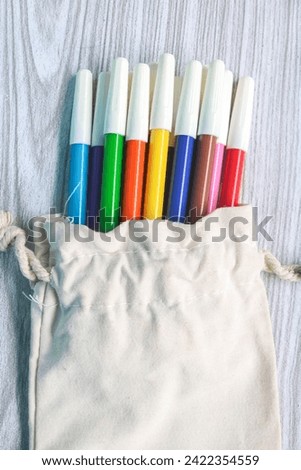 Colorful markers in a white drawstring bag Royalty-Free Stock Photo #2422354559
