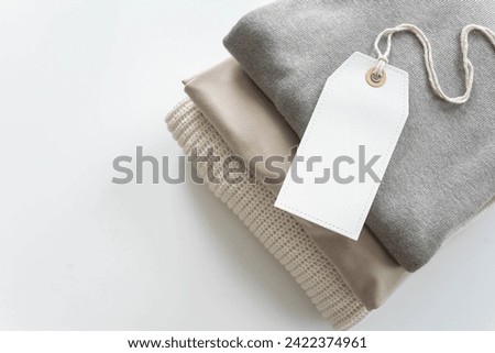 A neat stack of clean knitwear in neutral colors. Concept for sale, recycling and storage of clothing. Blank white label.