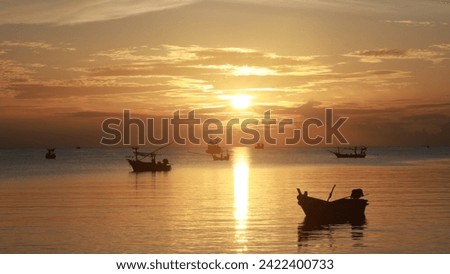 Picture of a fishing boat in the sea Background: The sun is setting in the evening. The sky is orange and gold.
