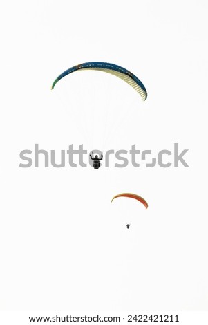 Two paratroopers isolated on white sky background. Paragliding. Extreme sports idea concept. Adventure, adrenaline. Feeling of freedom. Non-motorized aircraft. Vertical photo. Parachute. 