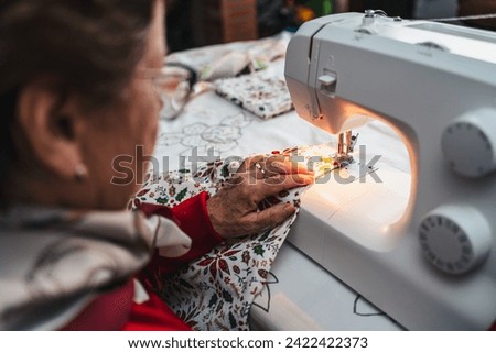 senior woman in red sewing a garment with sewing machine
