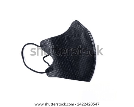 A black face mask lies against a white background, showcasing its textured fabric and ear loops. It's a common protective measure during the COVID-19 pandemic