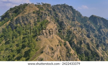 The Nature Valley mountain picture captures the majestic beauty of rugged peaks towering against a backdrop of clear blue skies. A winding trail leads through lush green forests, while cascading water