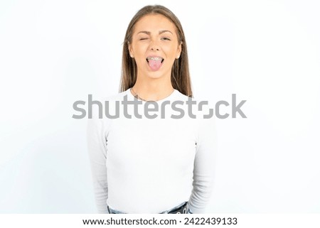 Young beautiful woman wearing braces sticking tongue out happy with funny expression. Emotion concept.