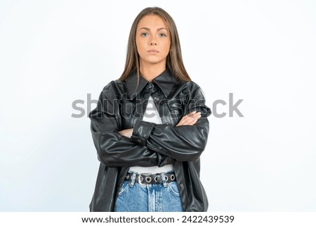 Serious pensive Young beautiful woman standing over white studio background feel like cool confident entrepreneur cross hands.