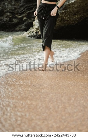 Image of a woman running on a sandy beach with slight waves. Mountains and fjords, travel to Krabi, Thailand, famous places, vacation, travel to Asia, take pictures under the lights in summer.