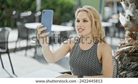Young blonde woman smiling confident having video call at coffee shop terrace