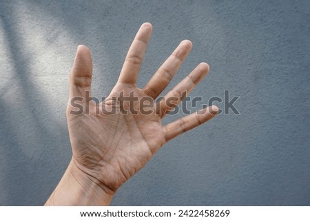 Closeup of hand showing five fingers isolated on grey background outdoor
