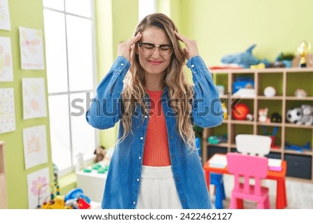 Young caucasian woman working as teacher at kindergarten suffering from headache desperate and stressed because pain and migraine. hands on head. 