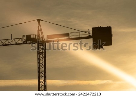 A curious sun ray is oriented towards a crane on a building site