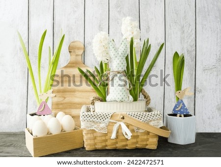 Decorative Easter composition on a wooden background, spring flowers hyacinths and cute wooden bunnies in a box with Easter eggs.  foreground.  Easter holiday concept, festive decor.