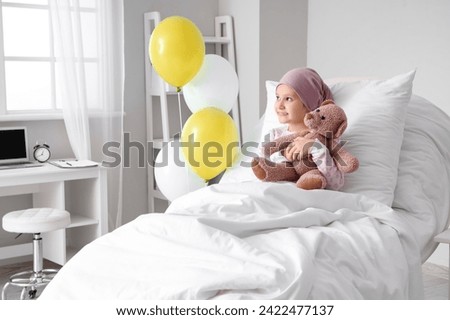 Little girl after chemotherapy with toy bear lying in bed at hospital. International Childhood Cancer Day Royalty-Free Stock Photo #2422477137
