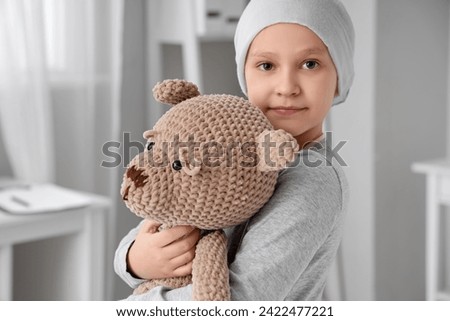 Little girl after chemotherapy with toy bear in clinic, closeup. International Childhood Cancer Day Royalty-Free Stock Photo #2422477221