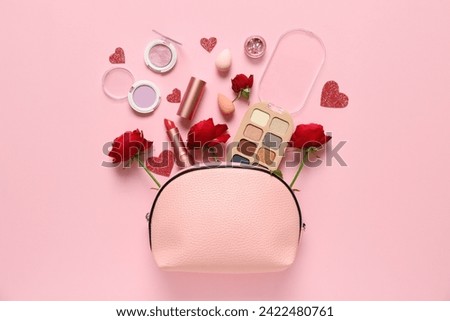 Cosmetic bag with make up products and red roses on pink background. Valentine's day celebration