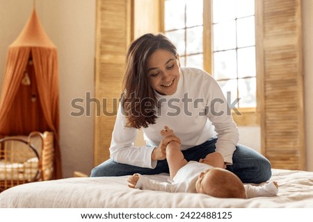 Happy mother and child in their bedroom, woman looking with admiration at her baby girl and smiling, enjoying moments of happiness Royalty-Free Stock Photo #2422488125