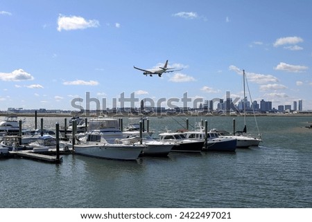 A plane over a marina, embracing the skies above a sea of anchored boats. The city skyline in the background. Royalty-Free Stock Photo #2422497021