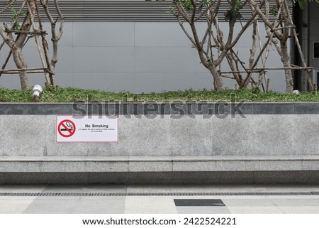 no smoking sign It is attached to a bench in front of the building.