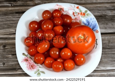 Tomato and cherry tomatoes, cherry tomato is a type of small round tomato believed to be an intermediate genetic admixture between wild currant-type tomatoes and domesticated garden tomatoes Royalty-Free Stock Photo #2422529191