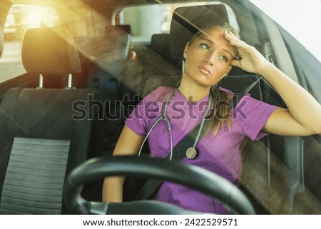 Shot of a young female doctor looking sad and tired, sitting in her car dusing the day. Shot of a beautiful young female nurse looking defeated and stressed resting in her car.