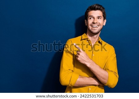 Photo portrait of attractive young man point look empty space wear trendy yellow clothes isolated on dark blue color background