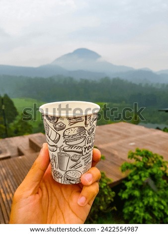 Close-Up of Coffee Cup on hand Against Landscape Scenery Mountain Hill Background.