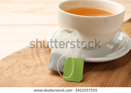 Tea bag and cup of hot beverage on light table, closeup. Space for text