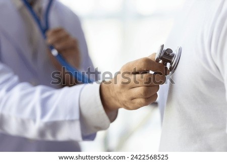 Doctor using stethoscope examining male patient for diagnosis in hospital examination room. Royalty-Free Stock Photo #2422568525